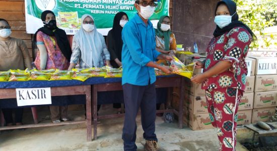 PUK PHS Papaso Bitcar siregar sedang menyerahkan minyak goreng kemasan kepada warga.