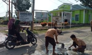 Siswa SMKN I Barumun bergotong royong memperbaiki Jl. Karya Pembangunan yang rusak dengan menempel semen disetiap lubang yang ada dibadan jalan