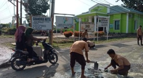 Siswa SMKN I Barumun bergotong royong memperbaiki Jl. Karya Pembangunan yang rusak dengan menempel semen disetiap lubang yang ada dibadan jalan