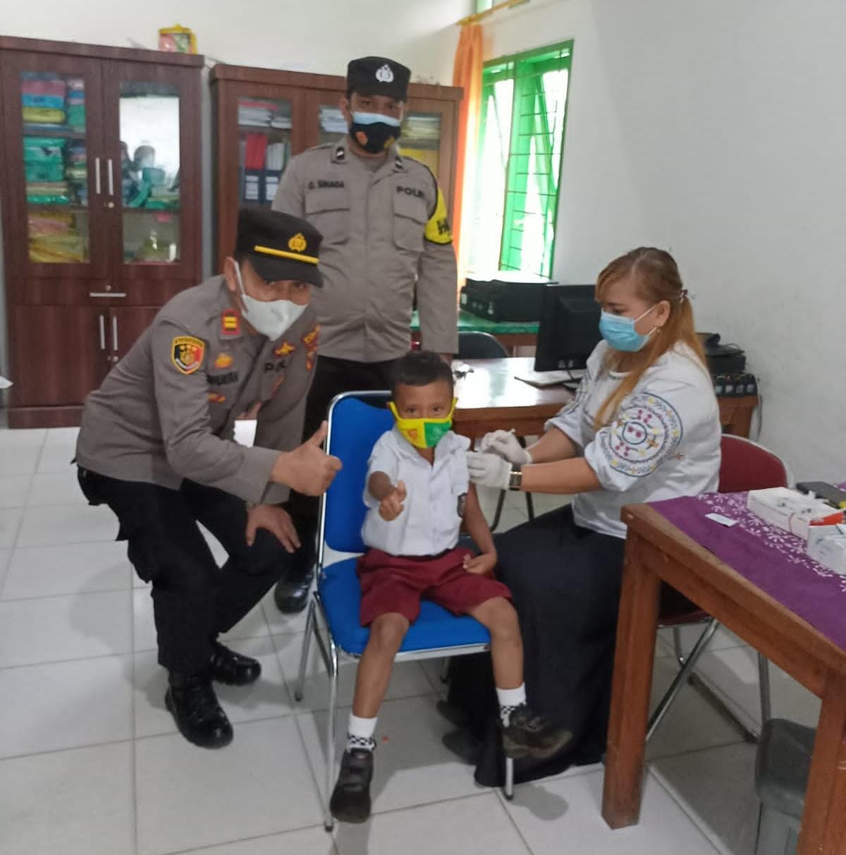 Kapolsek IPTU Domdom Panjaitan (kiri) memberi acungan jempol bersama siswa SD tanda memberikan semangat saat meninjau vaksinasi anak 6-11 tahun di Puskesmas Kotarih, Rabu (9/02/2022).(Foto Ar Manik/ Mitanews.co.id