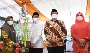 Bupati Sergai Darma Wijaya (kanan) didampingi Wabup Adlin Tambunan menyerahkan tropy juara umum MTQ kepada Camat Dolok Masihul, Muryani,SE.