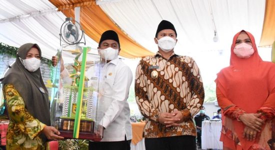 Bupati Sergai Darma Wijaya (kanan) didampingi Wabup Adlin Tambunan menyerahkan tropy juara umum MTQ kepada Camat Dolok Masihul, Muryani,SE.
