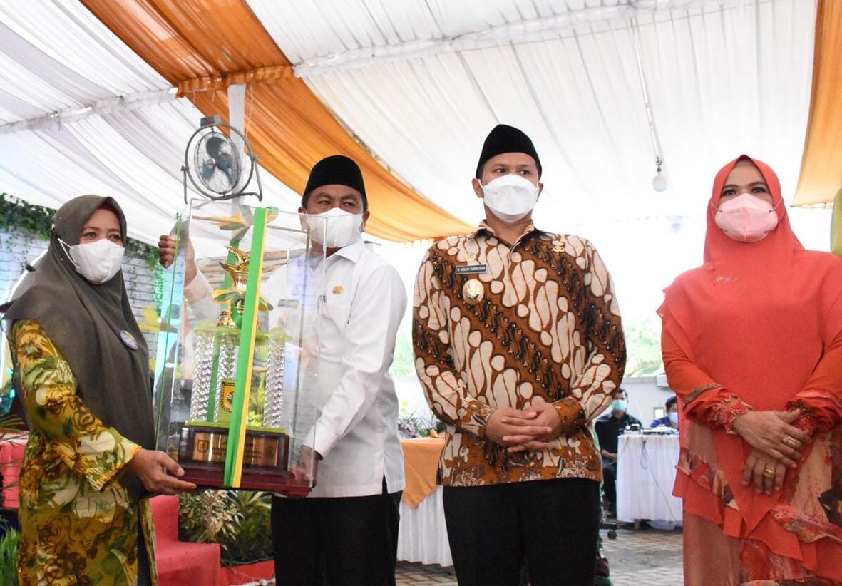 Bupati Sergai Darma Wijaya (kanan) didampingi Wabup Adlin Tambunan menyerahkan tropy juara umum MTQ kepada Camat Dolok Masihul, Muryani,SE.