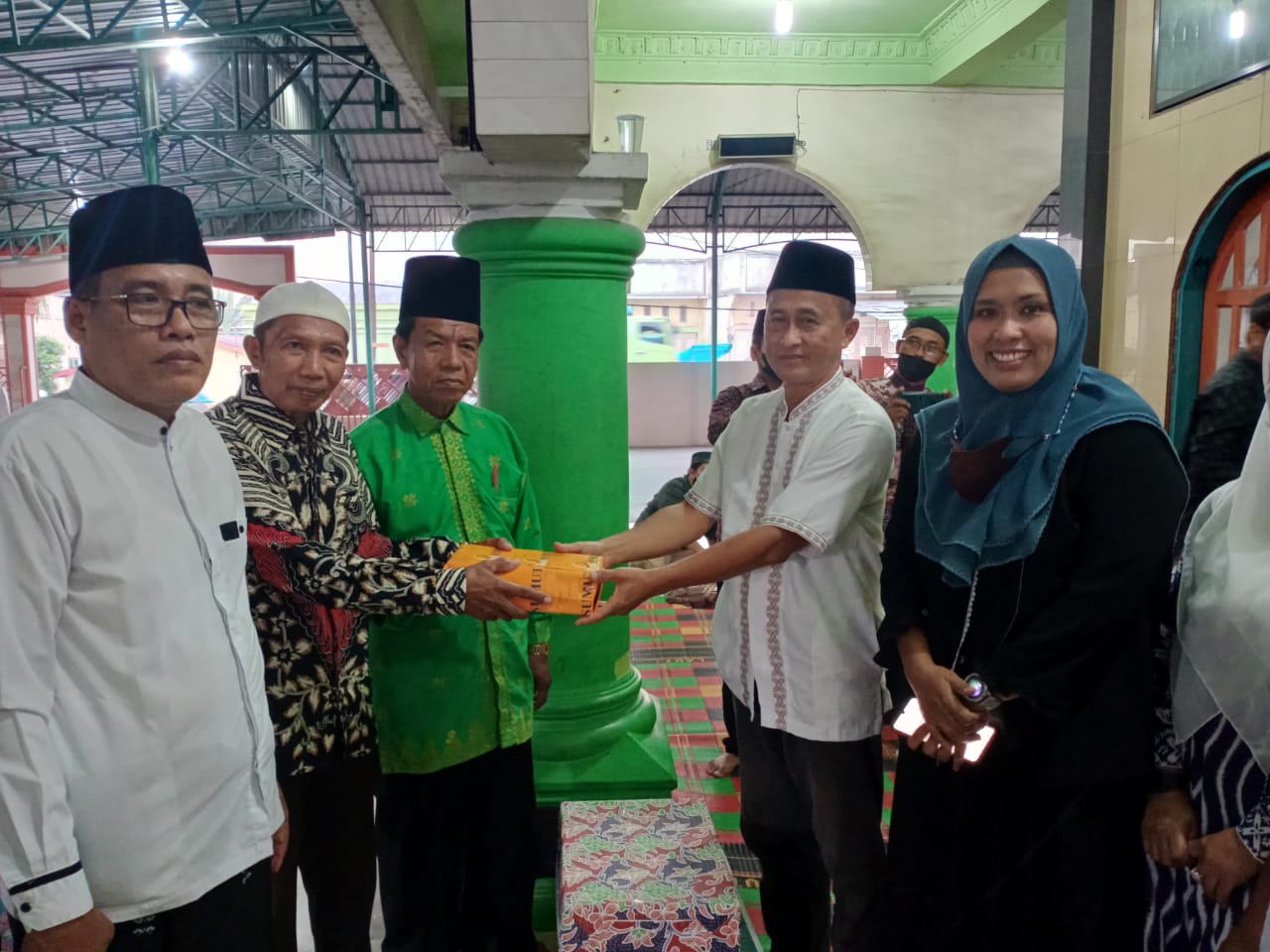 M Kahar Effendi,S.Sos Kepala Badan Kesbangpol (kanan) didampingi Kepala Dinas PMD Sri Rahmayani menyerahkan bingkisan kepada Ketua BKM Masjid Jami' Nurul Ihsan.( Photo: AR.Manik/Mitanews.co.id ).