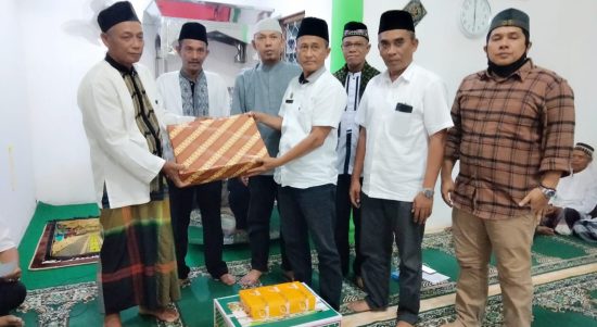 M Kahar Effendi,S.Sos Kepala Badan Kesbangpol (kanan) disaksikan Kades Mainu Tengah dan Camat Dolok Merawan Alpian Purba (nomor dua dan tiga dari kiri) menyerahkan bingkisan kepada Sukiman BKM Masjid Jami' Al Ikhlas Desa Mainu Tengah.