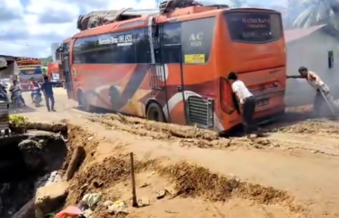 Bus angkutan umum terpuruk ke lubang badan jalinsun yang longsor di Kecamatan Hutaraja Tinggi.