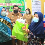 Ketua TP PKK Sergai Ny. Hj. Rosmaida Saragih Darma Wijaya (kiri),memberikan bantuan sembako saat membuka kegiatan Penguatan Kampung KB dan Percepatan Penurunan Stunting bertempat di Aula Kantor Desa Pekan Tanjung Beringin Selasa (19/4/2022).  