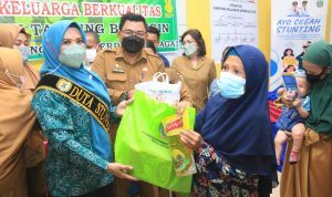 Ketua TP PKK Sergai Ny. Hj. Rosmaida Saragih Darma Wijaya (kiri),memberikan bantuan sembako saat membuka kegiatan Penguatan Kampung KB dan Percepatan Penurunan Stunting bertempat di Aula Kantor Desa Pekan Tanjung Beringin Selasa (19/4/2022).  