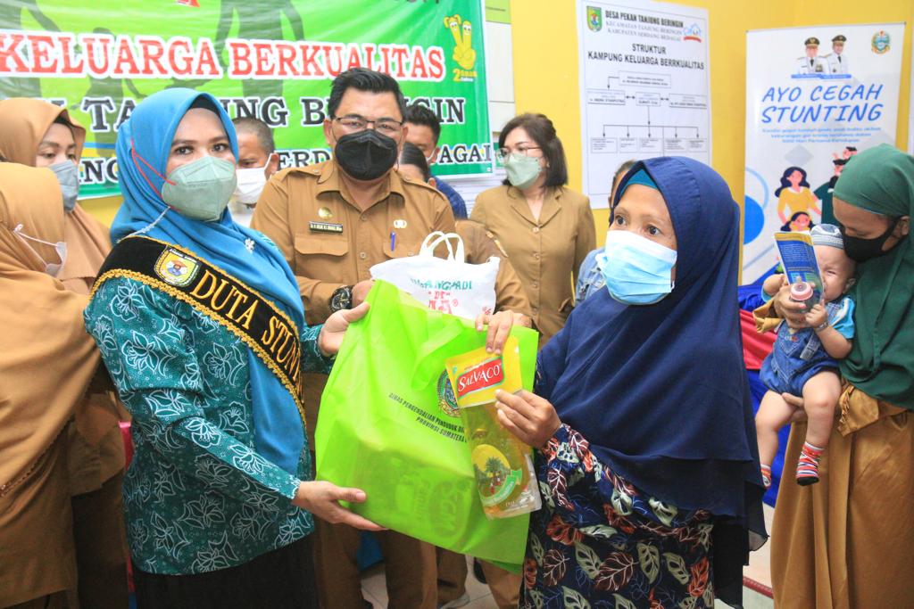 Ketua TP PKK Sergai Ny. Hj. Rosmaida Saragih Darma Wijaya (kiri),memberikan bantuan sembako saat membuka kegiatan Penguatan Kampung KB dan Percepatan Penurunan Stunting bertempat di Aula Kantor Desa Pekan Tanjung Beringin Selasa (19/4/2022).  