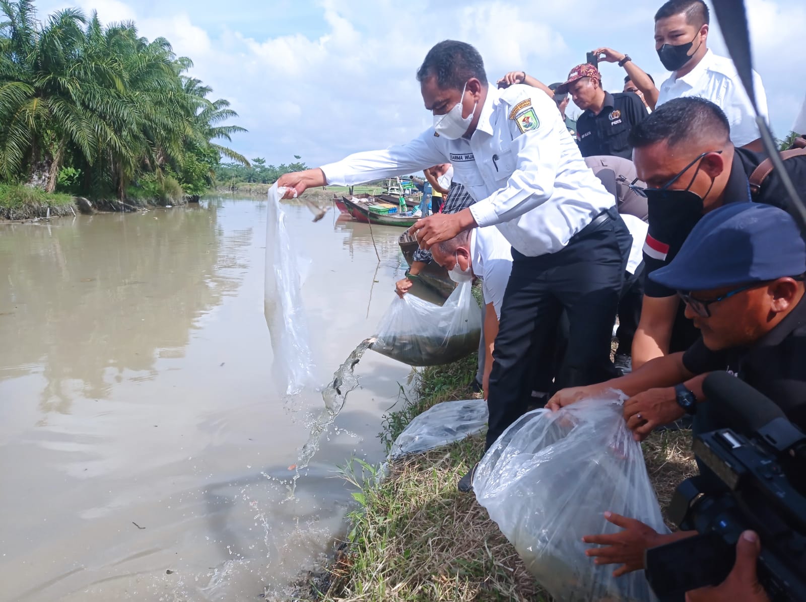 Bupati Sergai Darma Wijaya bersama Ketua PWI Sergai Edi Saputra (pakai topi) melakukan penebaran bibit ikan, dan labi-labi di Sungai Sei Belutu Kecamatan Tanjung Beringin.